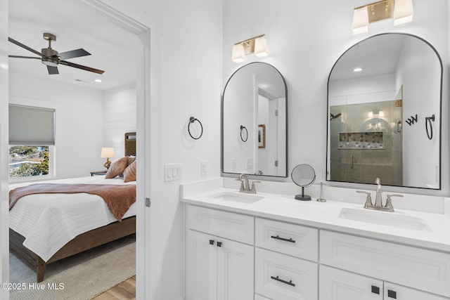 full bathroom with wood finished floors, a ceiling fan, a sink, a shower stall, and connected bathroom