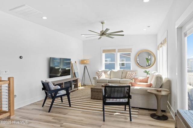 living area with light wood-type flooring, a healthy amount of sunlight, visible vents, and ceiling fan