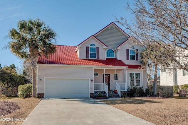 view of front facade featuring concrete driveway, metal roof, an attached garage, fence, and a porch