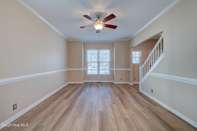 unfurnished living room featuring light wood-style floors, baseboards, stairway, and crown molding