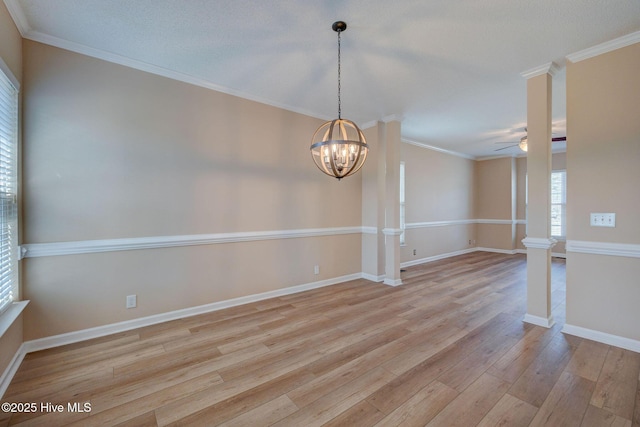 spare room with ceiling fan with notable chandelier, ornamental molding, light wood-type flooring, and decorative columns