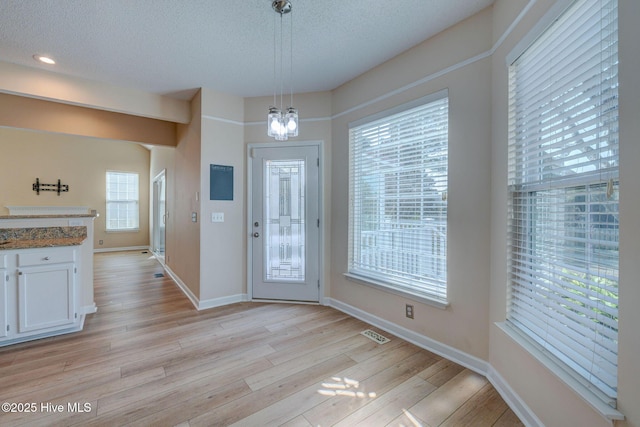 entryway featuring a textured ceiling, visible vents, light wood-style flooring, and baseboards