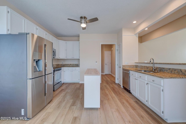 kitchen featuring appliances with stainless steel finishes, light wood-type flooring, a sink, and white cabinets