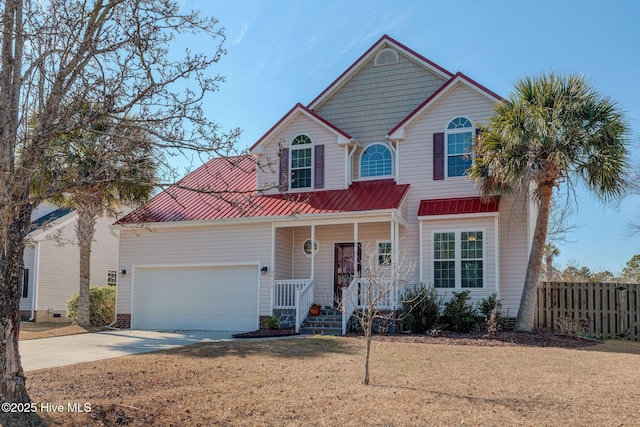 traditional-style house with metal roof, an attached garage, covered porch, fence, and driveway