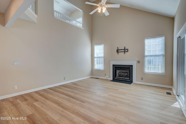 unfurnished living room featuring light wood-style flooring, visible vents, ceiling fan, and a fireplace with flush hearth