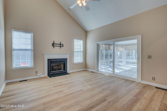 unfurnished living room featuring high vaulted ceiling, light wood-style flooring, visible vents, and a fireplace with flush hearth