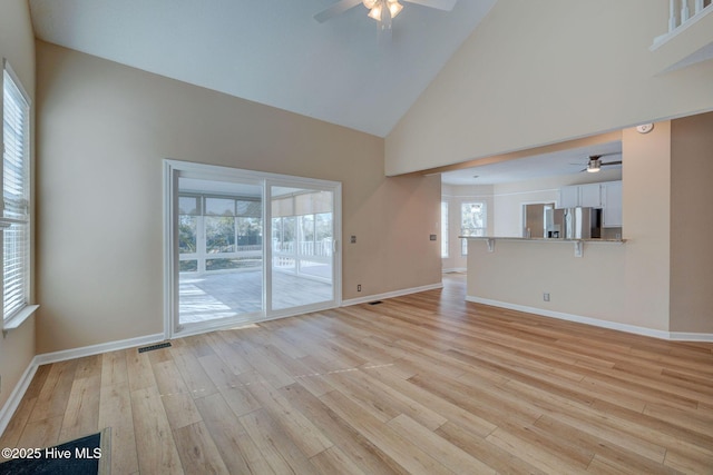 unfurnished living room with high vaulted ceiling, visible vents, light wood-style flooring, and baseboards