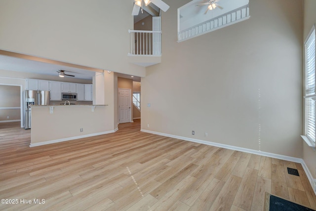 unfurnished living room with ceiling fan, light wood finished floors, and visible vents