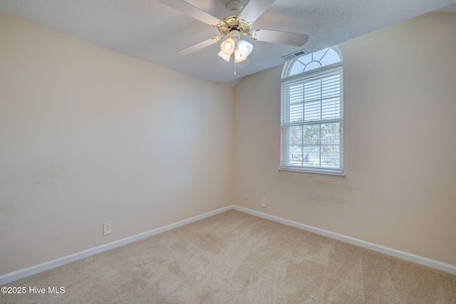 carpeted spare room featuring a textured ceiling, ceiling fan, visible vents, and baseboards