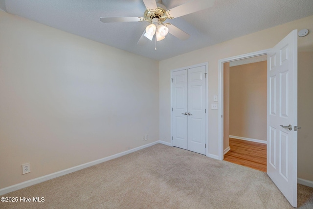 unfurnished bedroom with baseboards, a ceiling fan, carpet, a textured ceiling, and a closet