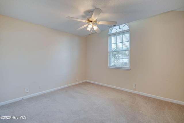 spare room featuring light colored carpet, ceiling fan, a textured ceiling, and baseboards