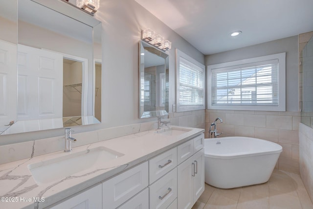 bathroom with tile patterned flooring, a sink, a freestanding bath, and double vanity