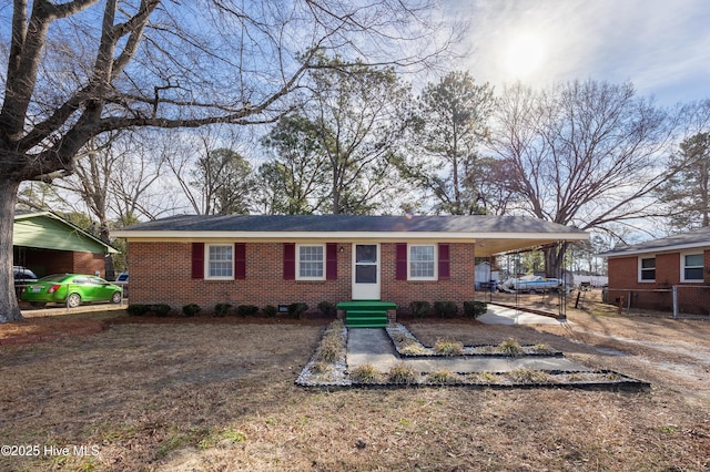 single story home featuring an attached carport, brick siding, fence, and driveway