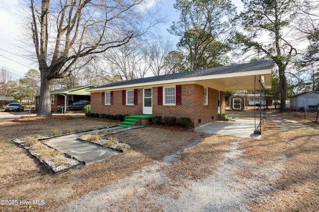 single story home featuring an attached carport, fence, driveway, crawl space, and brick siding