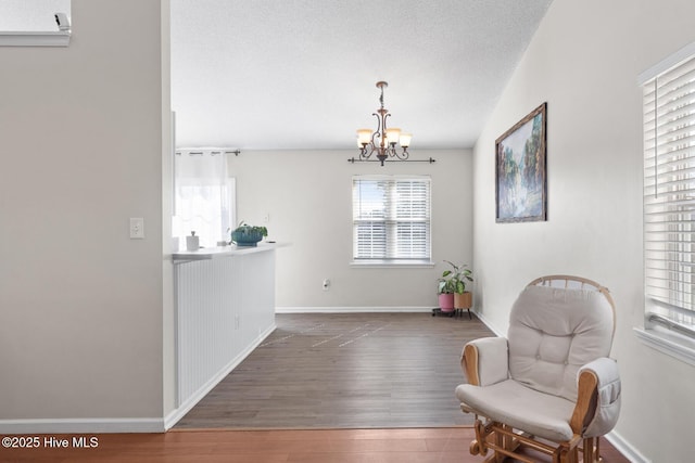 sitting room featuring a notable chandelier, a textured ceiling, baseboards, and wood finished floors