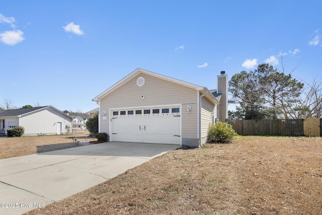 view of side of home with a garage, a chimney, fence, and concrete driveway