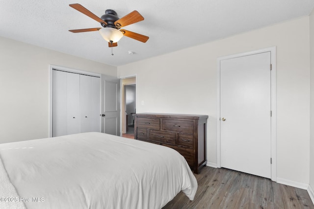 bedroom with a ceiling fan, a closet, baseboards, and wood finished floors