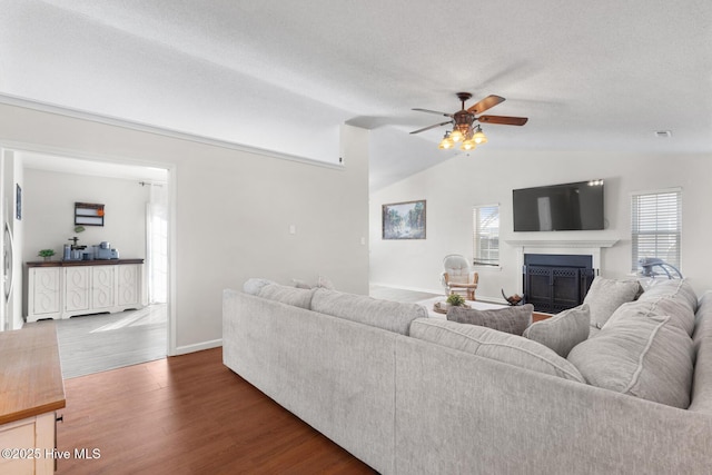 living room featuring a ceiling fan, wood finished floors, vaulted ceiling, a textured ceiling, and a fireplace