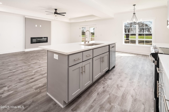 kitchen with gray cabinets, a sink, a glass covered fireplace, stainless steel appliances, and crown molding