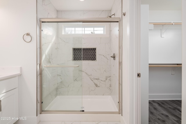 full bath featuring a marble finish shower, baseboards, a spacious closet, and vanity