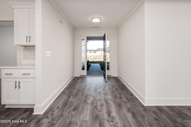 interior space with crown molding, dark wood-style floors, and baseboards