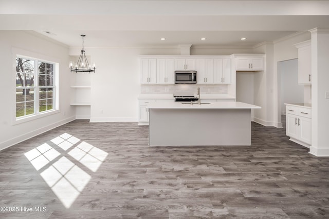 kitchen featuring a sink, light countertops, white cabinets, stainless steel microwave, and tasteful backsplash