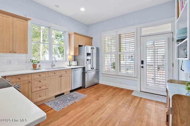 kitchen featuring decorative backsplash, appliances with stainless steel finishes, light countertops, light brown cabinetry, and a sink