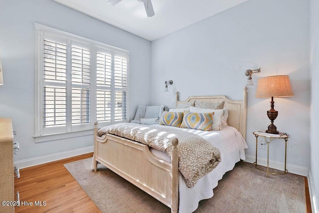 bedroom with light wood finished floors, multiple windows, baseboards, and ceiling fan