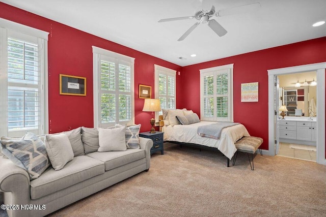 carpeted bedroom with ensuite bathroom and a ceiling fan