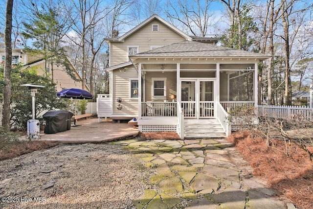 view of front of property with a sunroom, a shingled roof, fence, and a deck