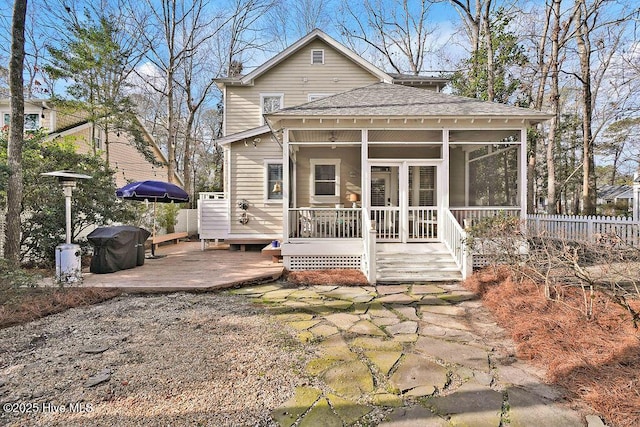back of property featuring fence, roof with shingles, a wooden deck, and a sunroom