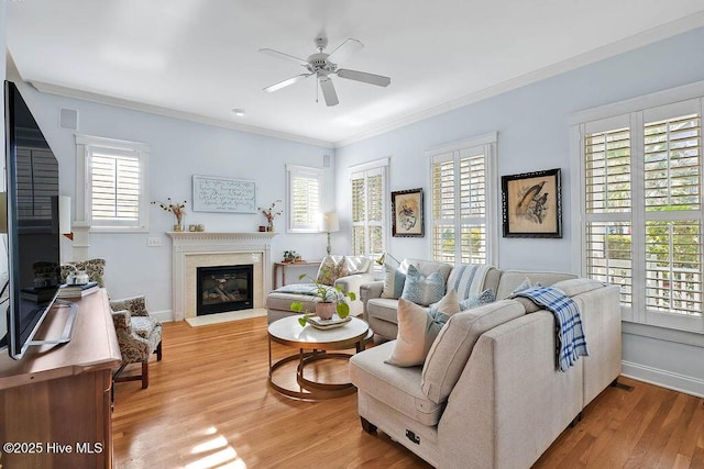 living area with light wood finished floors, plenty of natural light, a glass covered fireplace, and crown molding