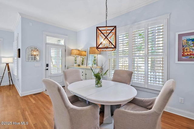 dining room featuring light wood-style floors, baseboards, a chandelier, and crown molding