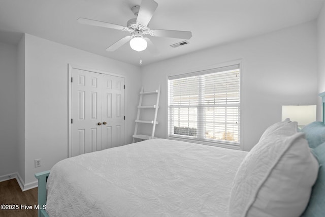 bedroom featuring visible vents, baseboards, a ceiling fan, dark wood-style floors, and a closet