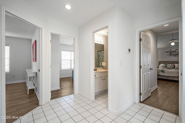 corridor with a sink, baseboards, and light tile patterned floors