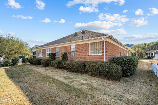 view of side of home with brick siding and a lawn