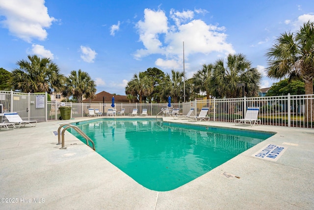 community pool with a patio area and fence