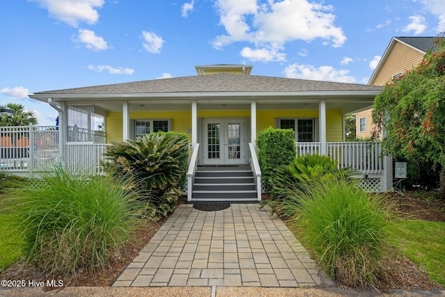 view of front of house with covered porch, a shingled roof, and french doors