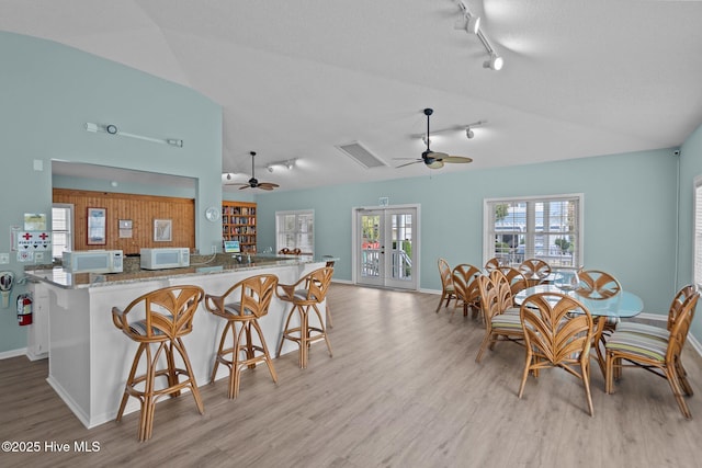 kitchen with a kitchen breakfast bar, white microwave, and light wood-style floors