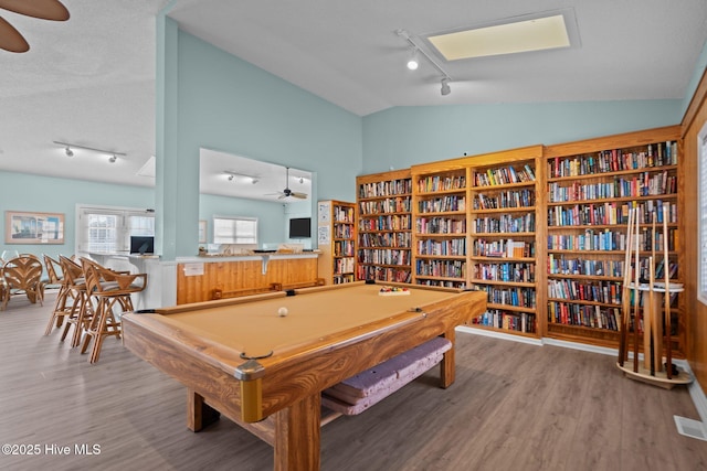 rec room featuring rail lighting, visible vents, a ceiling fan, vaulted ceiling, and wood finished floors