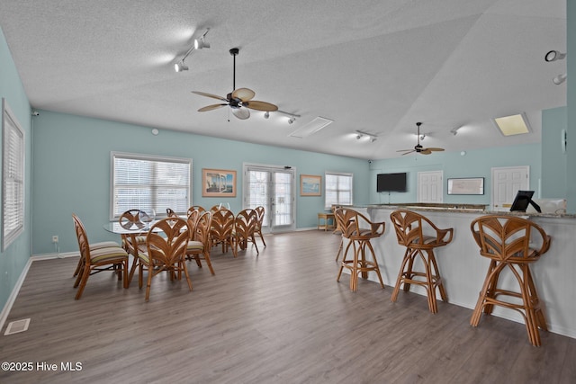 dining area with visible vents, ceiling fan, a textured ceiling, and wood finished floors