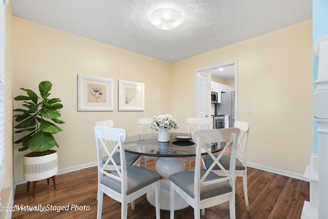 dining room with dark wood-style floors, a textured ceiling, and baseboards