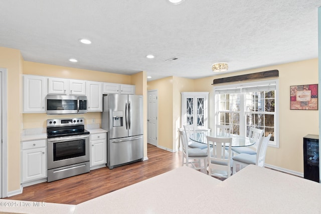 kitchen featuring visible vents, white cabinets, dark wood finished floors, stainless steel appliances, and light countertops