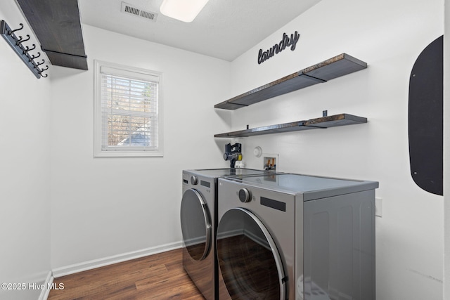 clothes washing area with laundry area, dark wood-style flooring, visible vents, baseboards, and washer and clothes dryer