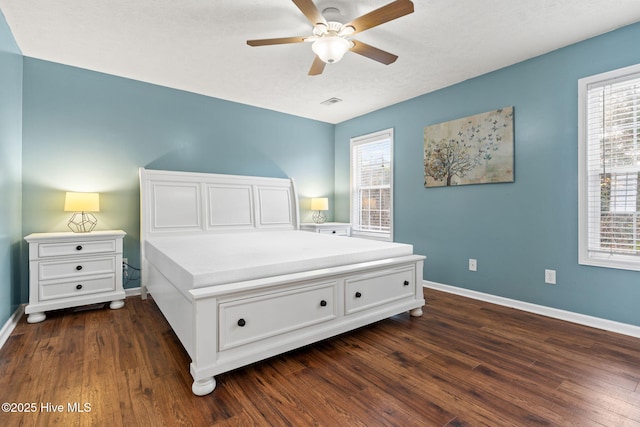 bedroom with ceiling fan, dark wood finished floors, visible vents, and baseboards