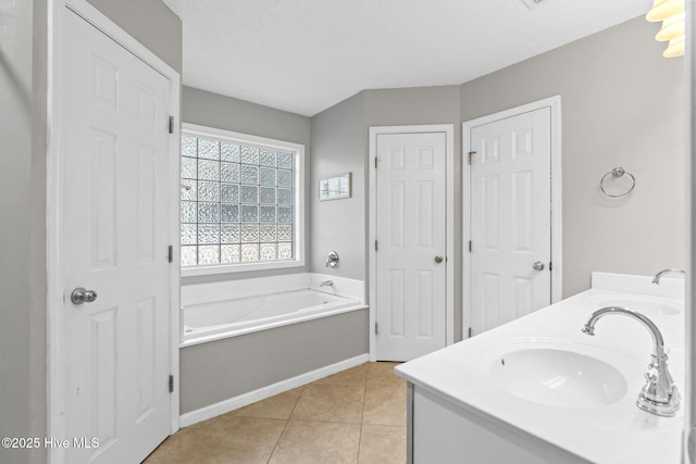 bathroom with double vanity, tile patterned flooring, a sink, and a bath