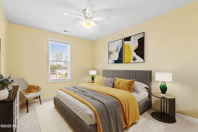 bedroom featuring visible vents, light colored carpet, a ceiling fan, a textured ceiling, and baseboards