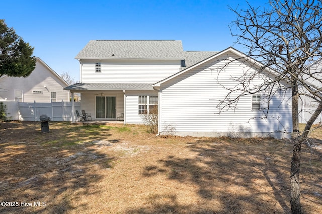 rear view of house featuring fence and roof with shingles