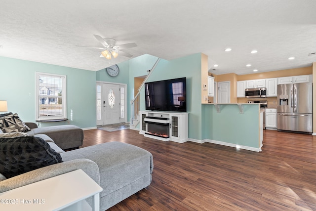 living room featuring lofted ceiling, recessed lighting, baseboards, dark wood-style floors, and a glass covered fireplace