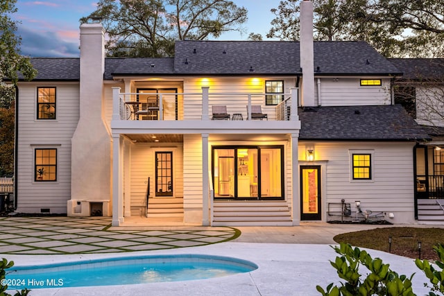 back of property with roof with shingles, crawl space, a patio area, a balcony, and an outdoor pool